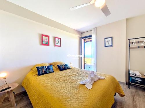 een slaapkamer met een bed met een gele sprei bij Bleu des Ô - Maison de 66m2 avec jacuzzi et sauna in Sainte-Marie