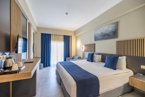 a hotel room with a large bed and a desk at Yasmin Bodrum Resort in Gumusluk