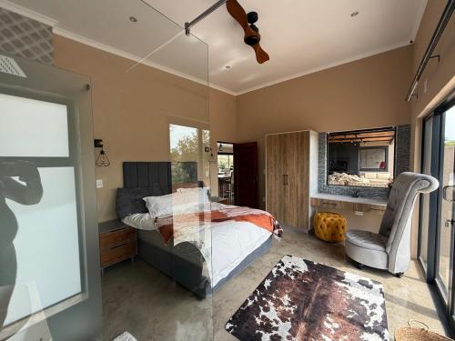 a bedroom with a bed and a chair in it at Blessed Lodge at Ingilozi Mabalingwe in Warmbaths