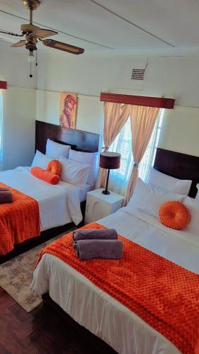 Un dormitorio con dos camas con almohadas naranjas sobre ellas. en Luxurious Family Carven!, en Rustenburg