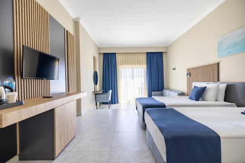 a hotel room with two beds and a tv at Yasmin Bodrum Resort in Gumusluk