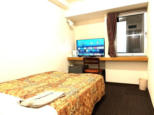 a hotel room with a bed and a desk with a computer at Hotel Tokeidai in Sapporo