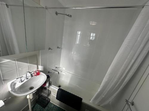 a white bathroom with a sink and a shower at Modern Crestwood Retreat - 2BR Near Canberra City in Queanbeyan