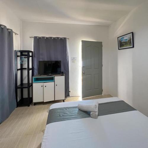 a bedroom with a bed and a television in it at Paradise Beach Guest House in Bantayan Island