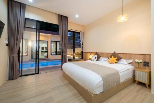 a bedroom with a large bed and a large window at Amaleena Pool Access Suites in Ban Bang Chak