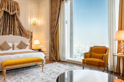 a bedroom with a bed and a chair and a window at The Bentley Luxury Hotel & Suites in Doha