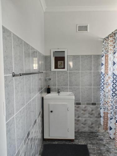 a bathroom with a white sink and a shower at Coral Cottage in Hilton