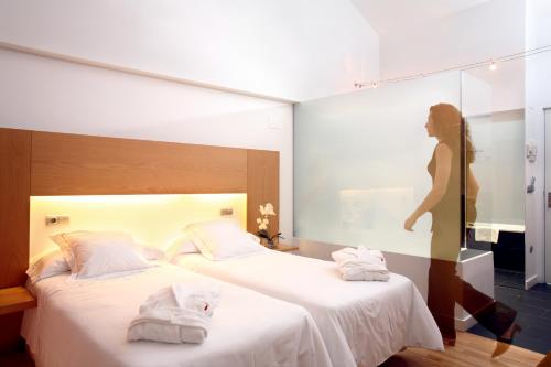 a hotel room with two beds and a woman in a mirror at Tierra de Biescas in Biescas