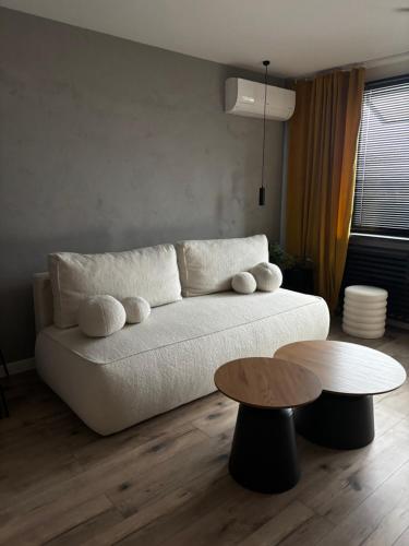 a living room with a white couch and two tables at Loft Re Design Apartament in Głogów