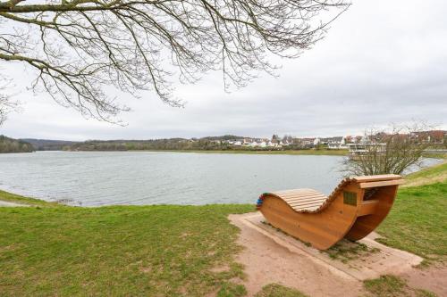 a wooden bench sitting next to a body of water at Schönes Ferienhaus Am Twistesee in Bad Arolsen