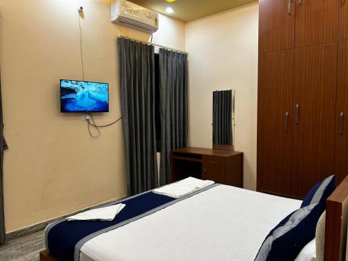 Un dormitorio con una cama y un televisor en la pared. en Shri Homes, en Varanasi