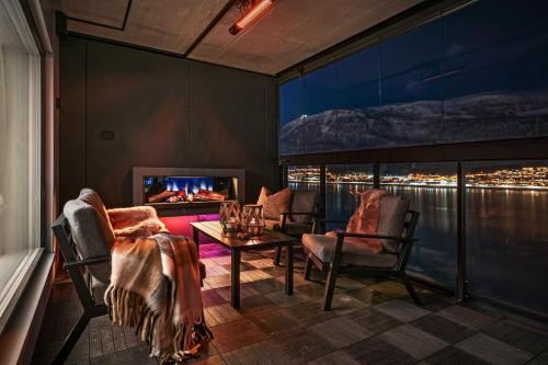 a room with chairs and a table and a tv at Premium Penthouse Sea & Mountain view Apartments in Tromsø in Tromsø