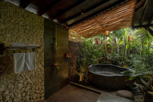 eine Badewanne im Bad mit Pflanzen in der Unterkunft Aksmi Suites & Villas in Bedahulu