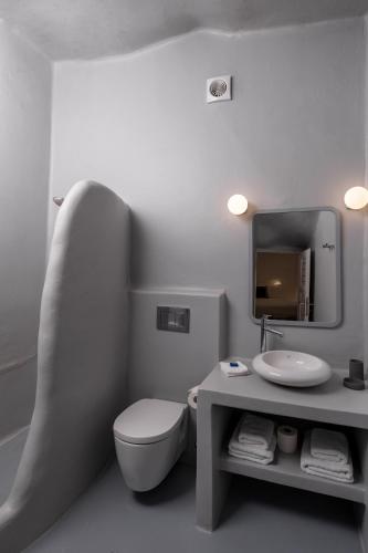 a bathroom with a toilet and a sink and a mirror at Cliff Side Suites in Firostefani