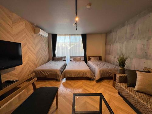 a living room with two beds and a tv at ペット可最大6名福井駅徒歩20分民泊 ピーチジョー足羽 in Fukui