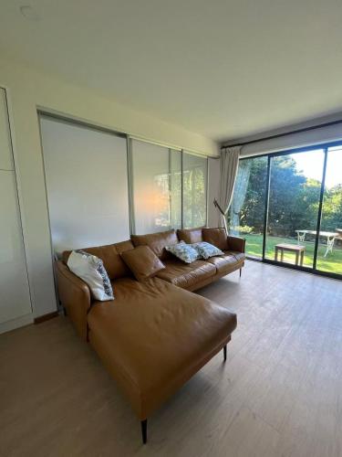 a living room with a leather couch and large windows at Almorah 2 bedroom in Auckland