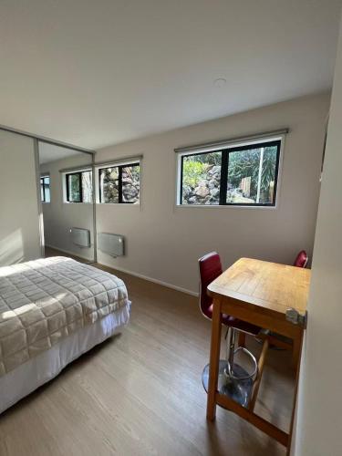 a bedroom with a bed and a table and windows at Almorah 2 bedroom in Auckland