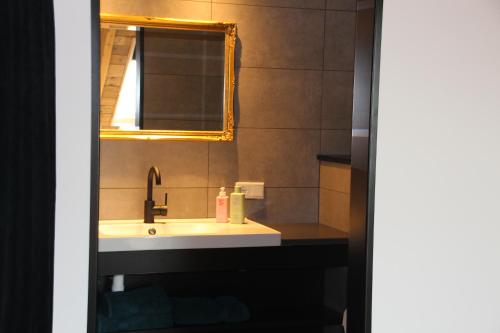 um banheiro com uma pia e um espelho em B&B Even Heukelom - Kamer 4 em Afferden