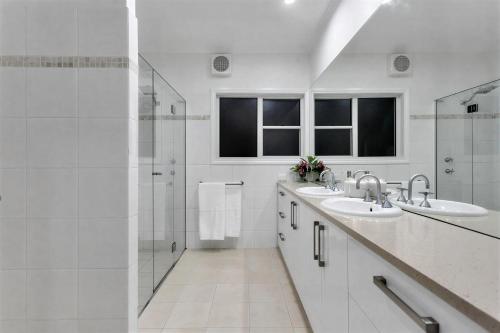 a white bathroom with two sinks and a shower at Luxury Resort Studio Apartment Retreat with Pool, Tennis & Alfresco 