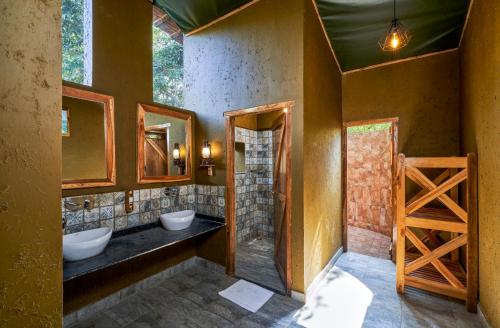 ein Badezimmer mit zwei Waschbecken und zwei Spiegeln in der Unterkunft WelcomHeritage Jungle Home Pench in Khawāsa