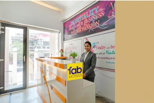 Un homme se tient près d'un comptoir avec un panneau indiquant les demandeurs d'emploi dans l'établissement FabHotel Raka Inn, à Allahābād