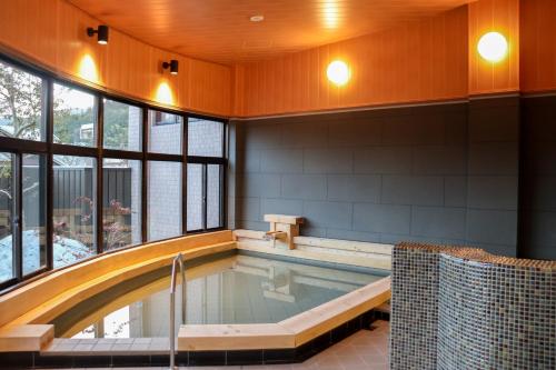 een zwembad in een gebouw met een groot raam bij クラフトホテルあば村 in Wada