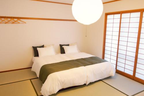 een slaapkamer met een groot bed en een groot raam bij クラフトホテルあば村 in Wada