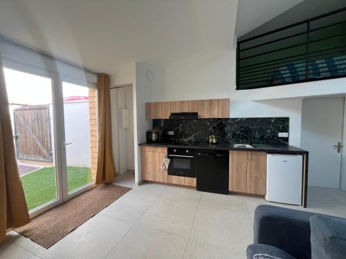 d'une cuisine équipée d'appareils noirs et d'une grande fenêtre. dans l'établissement La Vie est Belle, à Saint-Symphorien-sur-Coise