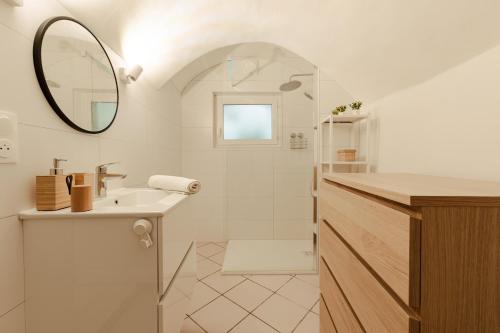 une salle de bain blanche avec un lavabo et un miroir dans l'établissement le cocon de Montélimar, à Montélimar