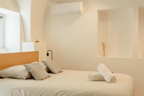 - un lit avec des oreillers blancs et une croix sur le mur dans l'établissement le cocon de Montélimar, à Montélimar