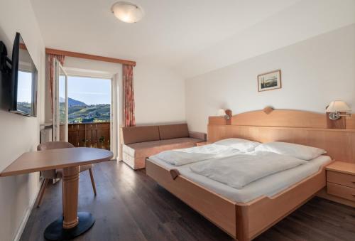 une chambre avec un lit, une table et une fenêtre dans l'établissement Petaunerhof, à Schenna