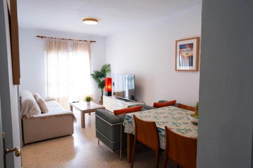 ein Wohnzimmer mit Tisch und Couch in der Unterkunft APARTAMENTO LOS BATELES - Frente a la playa in Conil de la Frontera