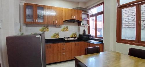 a kitchen with wooden cabinets and a table and a refrigerator at Hotel Silver Jubilee in Kathmandu