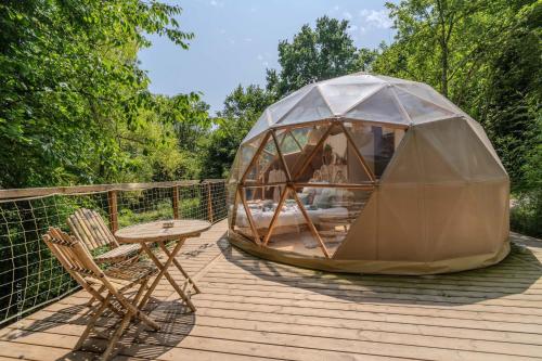 a dome tent on a deck with a table and chairs at Le Nid d'Eliyah dômes et suites avec jacuzzis 15min Disneyland in Nanteuil-lès-Meaux