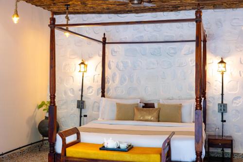 a bedroom with a four poster bed with a yellow bench at Granny's Den BY ELIVAAS in Dhanaulti