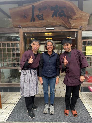 three people posing for a picture in front of a store at 檜湯の宿　松伯 in Aoki-gemi