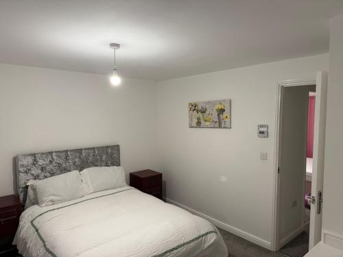 une chambre blanche avec un lit et un tableau sur le mur dans l'établissement Bettys Acklam hideout, à Middlesbrough