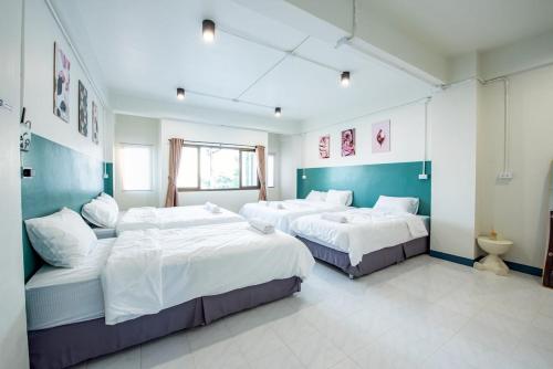 um quarto com três camas num quarto em Coral Beach House Rayong em Ban Noen Phra