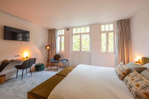 ein Schlafzimmer mit Bett, Schreibtisch und Fenstern in der Unterkunft B&B Achilles in Gent