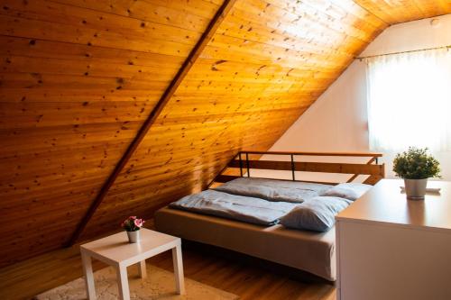 a bed in a room with a wooden ceiling at Siófoki Napfény Apartman in Siófok