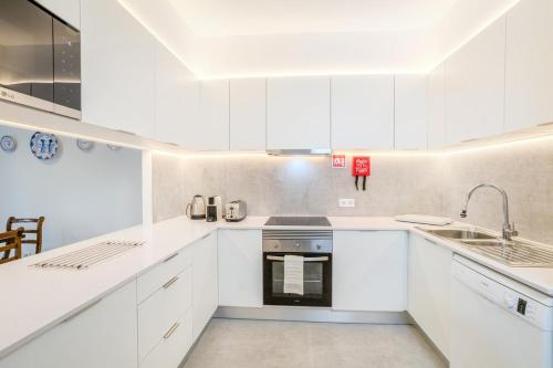 a white kitchen with white cabinets and a sink at GuestReady - Casa do Visconde in Rosto de Cão