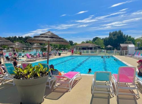 a large swimming pool with chairs and an umbrella at Mobil Home Camping 4* in Gastes