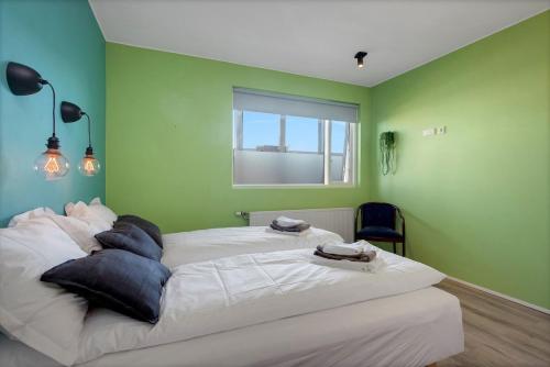 a bedroom with two beds with green walls and a window at Bright and Spacious Condo Downtown in Reykjavík