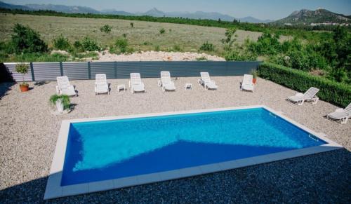 ein großer blauer Swimmingpool mit Liegestühlen in der Unterkunft Villa KOD BUBE in Ljubuški