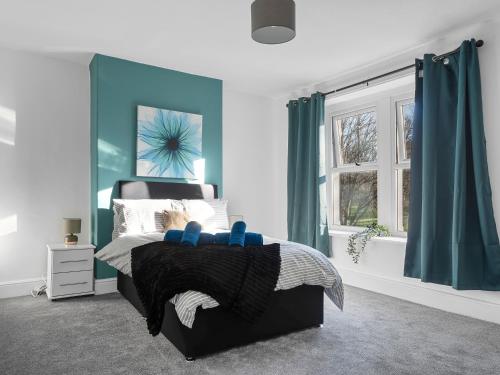 a bedroom with a bed with blue walls and a window at Harrington Haven 4 Bed Contractor Friendly House with Parking Workington in Workington