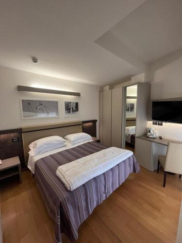 a bedroom with a bed and a desk and a television at Hotel Sporting in San Benedetto del Tronto