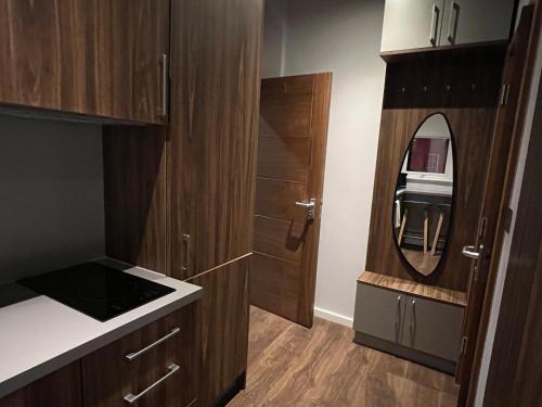 a small kitchen with wooden cabinets and a mirror at London Studio Retreat - Colney Hatch Lane in London