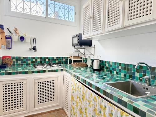 Una cocina con azulejos verdes y blancos en la encimera. en Dar Hikayat, en Tánger