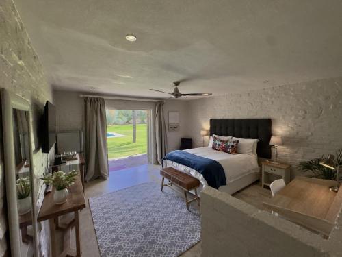 a bedroom with a bed and a living room at Hartland Country House Luxury Ensuite Rooms in Oudtshoorn