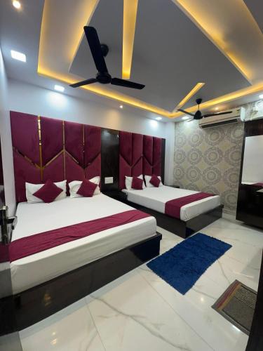 two beds in a room with purple and red at Hotel Peepal Tree Prayagraj in Prayagraj
